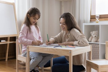 Genç, sevgi dolu bir anne, küçük kızıyla vakit geçirir modern çocuk odasında resim çizer, renkli kalemlerle çizer, konuşur, evde vakit geçirirken yaratıcı hobilerinden zevk alır. Çocuk gelişimi