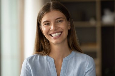 Yakın plan çekimde, doğal güzelliği olan güzel bir kadın, geniş bir gülümsemesi ve mükemmel bir teni var. Makyajı yok, kameraya bakıyor. Kendinden emin görünüyor. Muhteşem, genç, bağımsız kadın konseptinin portresi