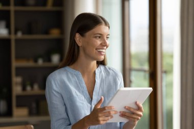 Dijital tablet tebessümüyle ofiste duran genç ve güzel iş kadını yeni uygulama kullanımının keyfini çıkarıyor, modern teknolojiyi kolay iş akışı için kullanıyor. E-ticaret, e-servis istemcisi kavramı