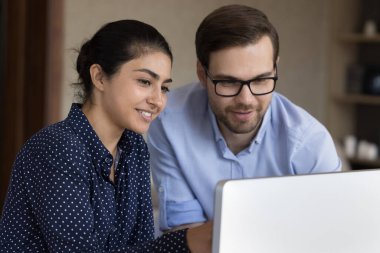 İki gülümseyen iş adamı birlikte bilgisayar üzerinde araştırma projesi raporu üzerinde çalışıyorlar. Mutlu Hintli genç bayan Avrupalı iş arkadaşları başarılı işbirliğinden memnun olan işi tartıştılar