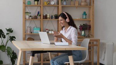 Kulaklıklı İspanyol iş kadını dizüstü bilgisayarla masada oturup sohbet ediyor, müşteriyle konuşuyor ya da video konferansında birinci sınıf öğrencileriyle konuşuyor. Okul harcı, sanal toplantı, eğitim modern teknoloji kavramını kullan