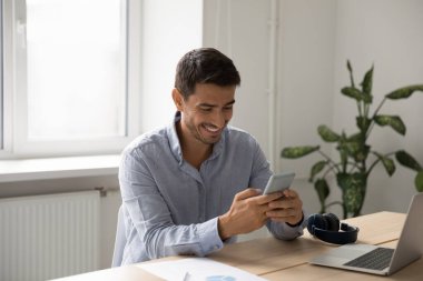 İş adamı masasında oturur, gülümser, akıllı telefon kullanır, e-postaya cevap verir, uzaktan sohbetin tadını çıkarır, iş ya da kişisel görüşme yapar. İş için mobil uygulama kullanımı, modern teknoloji kullanımı
