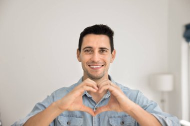 Sevgi, destek, ilgi, romantizm ifade eden, portre için dişlek tebessümle kameraya bakan, el ele romantik jestler yapan mutlu esmer adam.