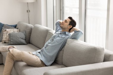 Sakin, yakışıklı Latin bir adam rahat bir evde rahat bir koltukta dinleniyor, yumuşak sırtına yaslanıyor, serin bir nefes alıyor, gözleri kapalı, kolları açık oturuyor, iş molasında eğleniyor, rahatlıyor, rahatlıyor.