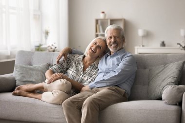 Neşeli olgun eşler modern oturma odasındaki rahat koltukta kameraya poz veriyorlar. Yavru patlama nesli çifti fotoshop, armonik ilişki, ömür boyu mutlu evlilik, bağlanma