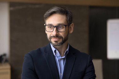 Gözlüklü, düşünceli, orta yaşlı iş adamı. Olumlu düşüncelere dalmış, şirketin başarısını, liderliğini, gelecek projelerini düşünüyor. Sadece ofiste poz veriyor.