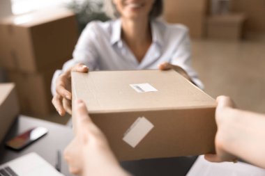 Ekin görünümlü mutlu orta yaşlı iş kadını nakliye ya da teslimat işlemi ile meşgul, paket kutusunu alıcıya teslim için hazır tutuyor. Lojistik iş akışı, küçük işletme, satış ve satın alma