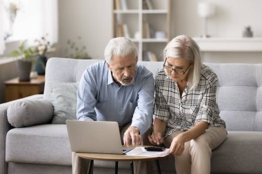 Ciddi bir çift kanepeye oturur, aylık giderleri sayar, konut kredisi ödemelerini kontrol eder, mali analizlerle, aile bütçesi yönetimiyle meşgul olur, parasızlık ve borç sıkıntısı çekerler.