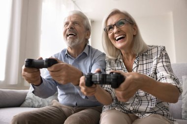 Aşırı mutlu, sorunsuz yaşlı eşler evde eğleniyorlar, joystick kullanıyorlar, oyun koruyucuları tutuyorlar macera oyunları oynuyorlar, tamamlamaya çalışıyorlar, mutlu oluyorlar. Modern teknoloji kullanan emeklilerin eğlencesi.