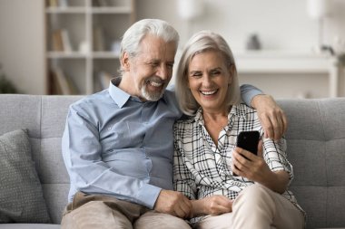 Neşeli yaşlı eşler evde vakit geçirirler, cep telefonu tutarlar, torunlarıyla görüntülü sohbet ederler, sosyal ağda komik videolar izlerler, aletlerle eğlenirler. Eğlence, uzaktan iletişim