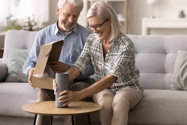 stock image Smiling wife holding vase received in parcel box, enjoy good quality express services and stylish decor item for home. Marketplace clients, electronic commerce services, positive feedback, e-shopping