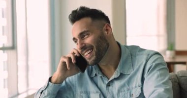 Mutlu, yakışıklı İspanyol adam cep telefonuyla konuşuyor, cep telefonuyla konuşuyor, dinliyor, telefon görüşmesinden zevk alıyor, gülümsüyor, gülüyor, akıllı telefondan iniyor.