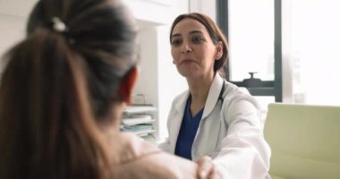 Genç, dost canlısı bayan cerrah hastayla konuşuyor, ameliyattan önce destek sağlayan omzuna dokunuyor, teşvik ediyor, tavsiye veriyor, etkili tedavi seçeneklerini paylaşıyor. Tıp, görev.,