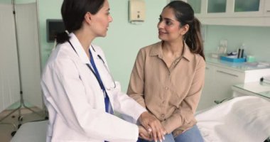 Üniformalı kadın cerrah genç hastaların ellerini tutarken klinikteki tedavi sürecinden bahsediyor, empati ve anlayış gösteriyor, cesaret verici sözler söylüyor, ameliyattan önce destek veriyor