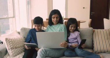 Pozitif genç Hintli anne ve iki küçük çocuk internet, medya servisi, dijital cihazlar, kucak bilgisayarı, akıllı telefon, tablet, oyun, evdeki çevrimiçi iletişimin keyfini çıkarıyorlar.