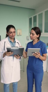 İki profesyonel tıp çalışanı, kadın iş arkadaşları fikir alışverişi için klinikte bir araya geldiler, hasta sağlığı test sonuçlarını gözden geçirdiler, iş yerindeki konuşma ve takım çalışmalarını konu alan bir çalışma programını tartıştılar.