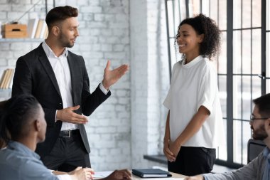 Utangaç şirket çalışanı iş toplantısında memnun CEO 'dan olumlu geri bildirim alıyor. Gülümseyen yönetici, kadın çalışana iş performansını iş arkadaşlarına iyi gösterdikleri için iltifat ediyor.