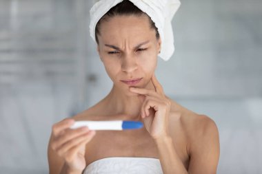 Banyodaki duştan sonra düşünceli genç bir kadın hızlı bir tıbbi hamilelik testi yapar, pozitif sonuç için bekler, binlerce yıllık düşünceli bir kadın yumurtlama çubuğu, lvf, kısırlık konsepti,