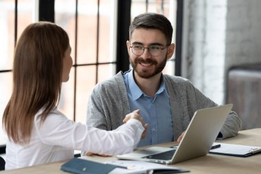 Kadın müşteri, erkek kredi memuruyla el sıkışıyor. Müşteri, banka çalışanlarına finansal tavsiyeleri için teşekkür ediyor. Genç ve mutlu girişimciler bir anlaşma yapıyor. CEO, yeni çalışanı modern şirkete kabul ediyor.