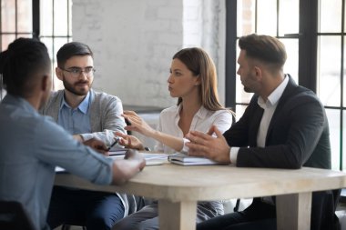 Girişimciler için bir atölye çalışması düzenleyen genç işletme koçu, onlara etkili iletişim teknikleri öğretiyor ve tavsiyelerini paylaşıyor. Şirket toplantısında fikir alışverişinde bulunan kadın çalışan.