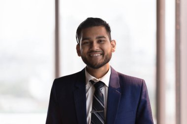 Resmi takım elbiseli Hintli iş adamı resmi pozu vermiş kameraya bakıp kariyerinin gelişmesi, terfi etmesi ve şirket pozisyonunda işe alınmasıyla gurur duyacak şekilde gülümsüyor. Proje lideri, CEO portresi konsepti