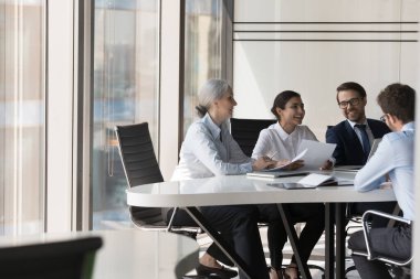 Neşe dolu farklı iş adamları toplantı odasında toplanıp mevcut işleri çözüyor, proje analizleri yapıyor, resmi toplantıda strateji geliştiriyor. Müzakereler, işbirliği, takım çalışması, yönetim kavramı