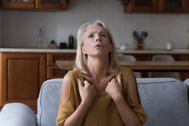 Yaşlı kadın evde yüksek sıcaklıktan muzdarip, kendini iyi hissetmiyor, aşırı ısınmış ve sağlıksız görünüyor. Yaşla ilgili hormonal değişiklikler, menopoz, iklim kontrolü, klima sistemi konsepti