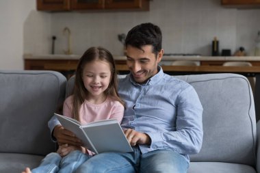 Genç baba, 6 'lı yaşlardaki tatlı kızına kitap okuyor. Kanepeye oturup, boş zamanlarını değerlendiriyor ve evde eğleniyor. Babalık, yetiştirilme, çocuk gelişimi, zeka kavramı