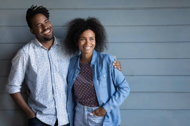 Mutlu Afrikalı Afrikalı Amerikalı genç çift sarılıyor, gri stüdyo ahşap arka planda duruyor, uzaktan bakıyor, düşünceli bir adam ve kadın birlikte güzel bir gelecek hayal ediyor, birlikte plan yapıyorlar.