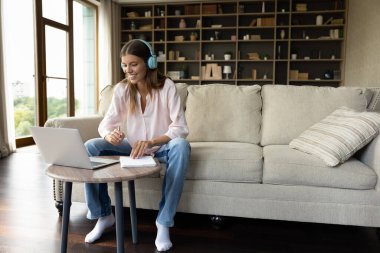 Neşeli, kablosuz kulaklık takmış, internetten web sitelerini izleyen, yabancı dil okuyan, çevrimiçi sınıfa katılan, öğretmenle video konuşması yapan, sesli ders notları yazan Z sınıfı öğrencisi kız.