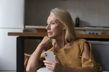 Düşünceli, bunalımlı, cep telefonu kullanan, sorunları düşünen, online sohbet mesajlarından kötü haberler, arama, sosyal medya ağı, başka yere bakan yaşlı bir bayan. İletişim, yaşlılık kavramı