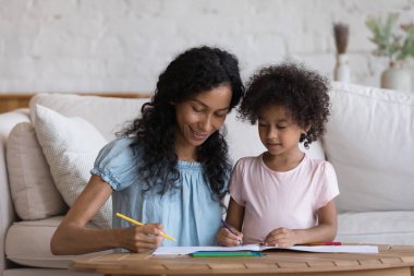 Küçük kız evde annesiyle resim dersi alıyor, rahat bir oturma odasında oturup çizim defterindeki renkli kalemlerle resim çiziyor ve aile yaratıcılığının tadını çıkarıyor. Geliştirme, eğlence konsepti
