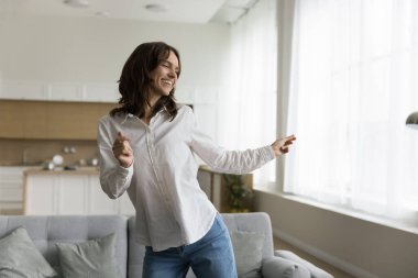 Sorunsuz kadın kiracı ya da ev sahibi rahat stüdyo dairesinde dans ediyor, boş zamanlarını evde geçiriyor, favori müziğe geçiyor, oturma odasında tatil yapıyor. Hobi, aktif eğlence, canlılık. Hayatın tadını çıkar.