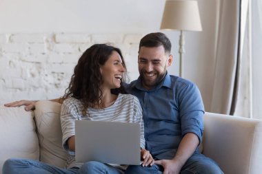 Milenyum eşleri gülerek kanepede dizüstü bilgisayarla oturur, dijital yayın hizmetlerinde eğlenceli aile filmleri izler, internette eğlenir, uzaktan kumandalı e-servis konseptinin keyfini çıkarırlar.