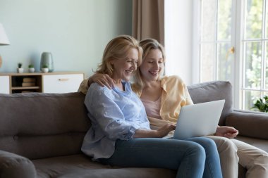 Mutlu sarışın, son sınıf annesi ve film izleyen genç yetişkin kız dizisi dizüstü bilgisayarda yayınlanıyor, gülüyor, video görüşmesinde konuşuyor, kablosuz internet iletişiminin keyfini çıkarıyor.
