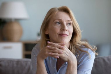 Düşünceli, olgun, 60 'lı yaşlarda, sarışın bir kadın. Kanepede oturuyor, çenesine yaslanıyor, güzel düşüncelerle kafasını çeviriyor, gelecekteki emeklilik planlarını düşünüyor, boş zamanlarının tadını çıkarıyor.