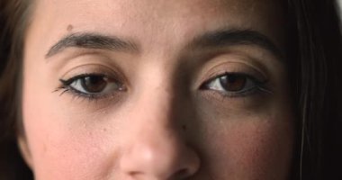 Göz kapağında ben, göz kalemi ve kirpiklerinde rimel olan 20 'li yaşlardaki Asyalı genç kadının kahverengi gözleri. Güzellik bakımı kadın modeli kameraya bakıyor, mutlu oluyor, gülümsüyor, üst tarafı kırpılmış.