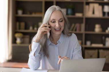 Ofiste çalışan çekici, yaşlı bir iş kadını iş görüşmesi yapar, gülümser, cep telefonundan hoş sohbetler eder, müşteriye uzaktan yardım eder. Modern teknoloji, iletişim konsepti