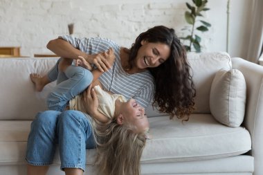 Neşeli anne, mutlu, heyecanlı küçük kızıyla dövüş oyunu oynuyor, sarılıyor, gıdıklıyor, kucağına çocuk alıyor, yüksek sesle gülüyor, bağırıyor, olumlu duygulardan keyif alıyor, aile oyun zamanı.