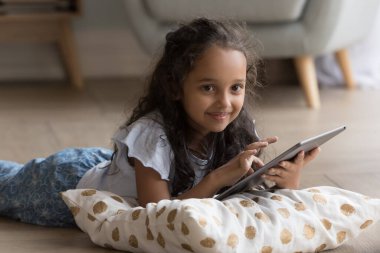 Güzel küçük Hintli kız dijital tablet kullanıyor, internette oyunlar oynuyor, internette tek başına vakit geçiriyor. Z jenerasyonu ve modern kablosuz teknoloji kullanımı, ebeveyn kontrol yazılımı, eğlence için uygulamalar