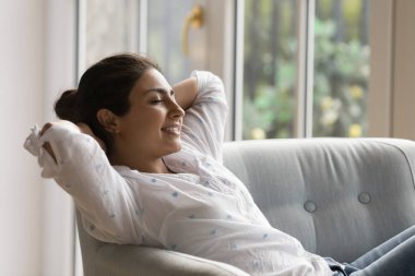 Huzurlu Hintli kadın, rahat koltuğa yaslanmış, klimalı oturma odasında temiz hava soluyan rahatlığın tadını çıkarıyor. Modern dairenin sahibi olan kiracı, boş vakitlerinde evde mola verir. Stressiz hafta sonu