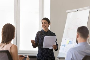 Mutlu motive olmuş Hintli şirket öğretmeni kadın stajyerleri eğitiyor, çalışanlara öğretmenlik yapıyor, öğrencilere koçluk yapıyor, pazarlama grafiklerinde ofis toplantılarında konuşma yapıyor.