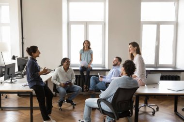 Neşeli motivasyonlu iş ekibi ofiste başarılı projeleri tartışıyor, beyin fırtınası yapıyor, konuşuyor, gülüyor, yüksek satış sonuçlarını kutluyor. Çok ırklı yaratıcı grup birlikte çalışıyor.