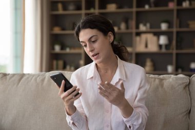 Güzel Latin bir kızın cep telefonuyla konuşması, koltuktan video konuşması, akıllı telefonu tutması, ekranda konuşması, akıllı telefon web kamerası. Blogger video kaydı. İletişim konsepti