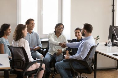 Kendine güvenen neşeli Hintli ve Kafkasyalı iş arkadaşları ofiste buluşurken el sıkışıyorlar, gülüyorlar, gülümsüyorlar. Çeşitli grup terapi arkadaşları tanınmak için tokalaşıyor