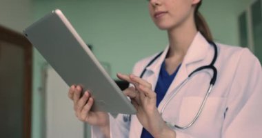 Tablet kullanan kadın terapist, klinik notları, tedavi planlarını kaydeden, test siparişlerini veren, ilaç yazan, hastalarla sanal konsültasyonlar yapan, kapatan. Modern teknoloji ve sağlık sigortası