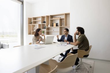 Çeşitli iş adamları paydaşları konferans masasında toplanıp iş etkileşimini tartıştılar. Profesyonel yöneticilerden oluşan bir grup, çalışma ofisinde genç Hintli erkek meslektaşlarının fikirlerini dinliyor.