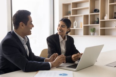 Gülen genç Hintli yöneticiler çeşitli cinsiyetlerden şirket çalışanları bilgisayar uygulaması kullanarak eğlenceli iş durumları hakkında sohbet ediyorlar. İki iş arkadaşı iş yerinde eğleniyor.