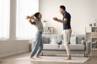 Heyecanlı aktif çift daire kirasını kutluyor, gayrimenkul satın alıyor, evde birlikte dans ediyor şık oturma odasında, iki kişilik partinin tadını çıkarıyor, sarılmak için ellerini açıyor, gülüyor.