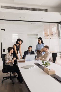 Çeşitli iş arkadaşları ve Hintli patronlardan oluşan bir ekip büyük masada toplanıyor, online projeyi tartışıyorlar, dizüstü bilgisayar kullanıyorlar, konuşuyorlar, gülüyorlar, gülüyorlar, takım çalışması stratejisinde beyin fırtınası yapıyorlar.